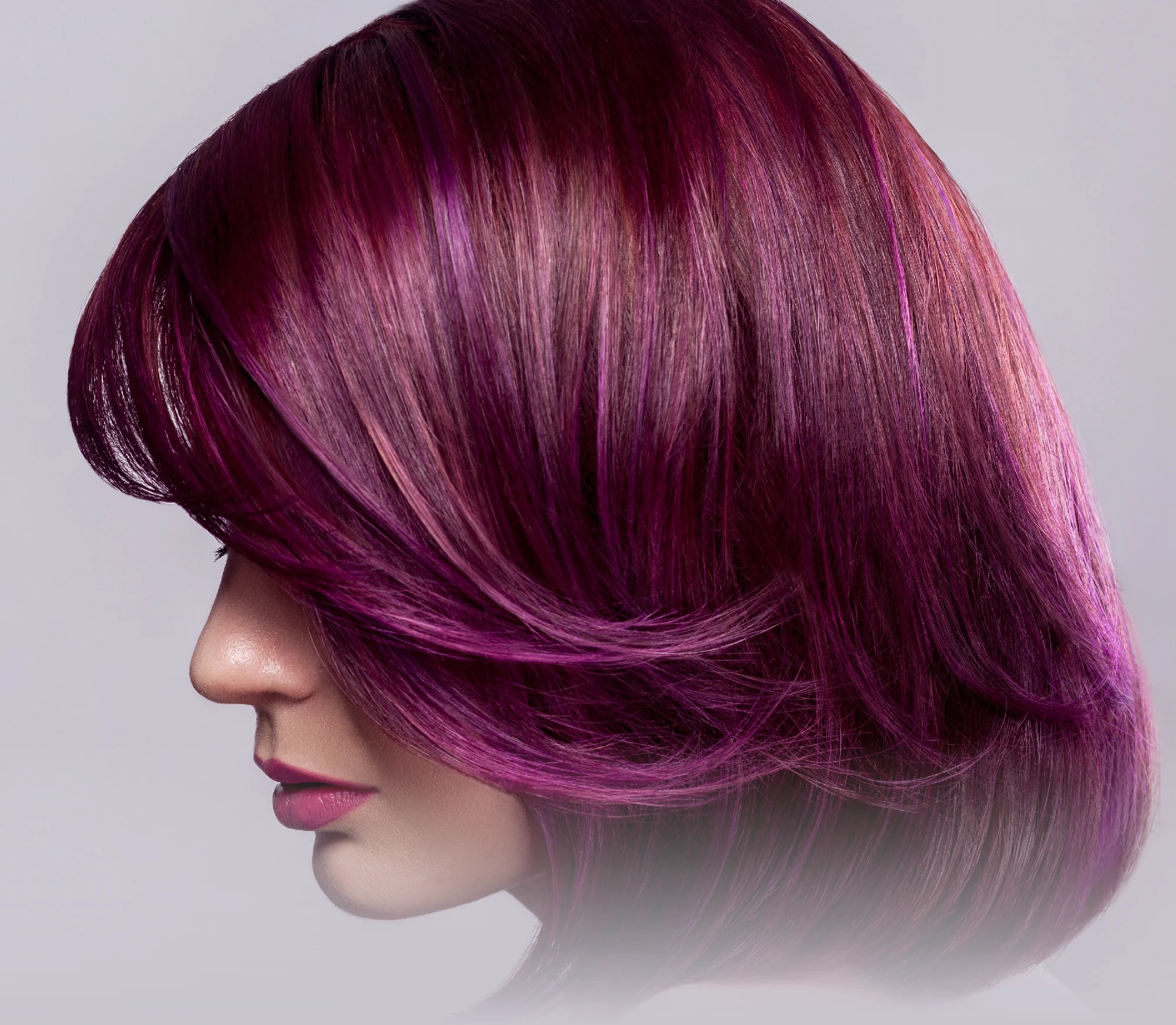 Side profile of a woman with smooth magenta and purple-toned bob haircut with layered styling